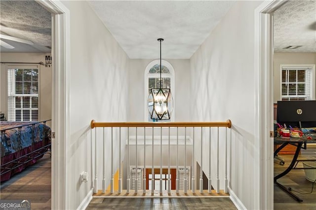 interior space with a chandelier, hardwood / wood-style floors, a textured ceiling, and a wealth of natural light