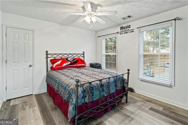 bedroom featuring hardwood / wood-style flooring, ceiling fan, and a textured ceiling