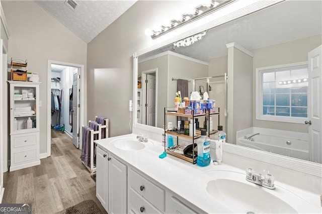 bathroom with vaulted ceiling, plus walk in shower, hardwood / wood-style flooring, vanity, and a textured ceiling