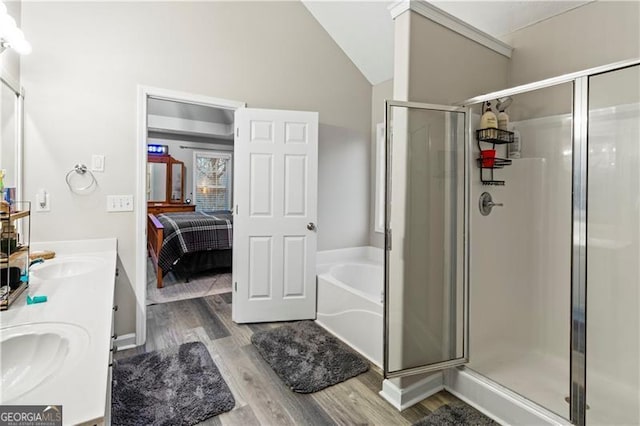 bathroom featuring wood-type flooring, shower with separate bathtub, vaulted ceiling, and vanity