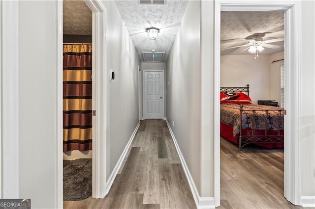 hallway featuring hardwood / wood-style floors and a textured ceiling