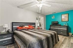 bedroom with a textured ceiling, light hardwood / wood-style flooring, and ceiling fan