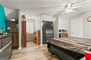 bedroom with ceiling fan, a textured ceiling, and light hardwood / wood-style flooring