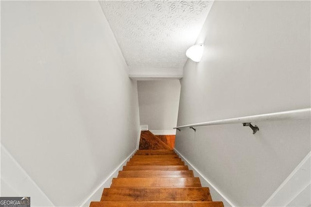 staircase featuring hardwood / wood-style floors and a textured ceiling