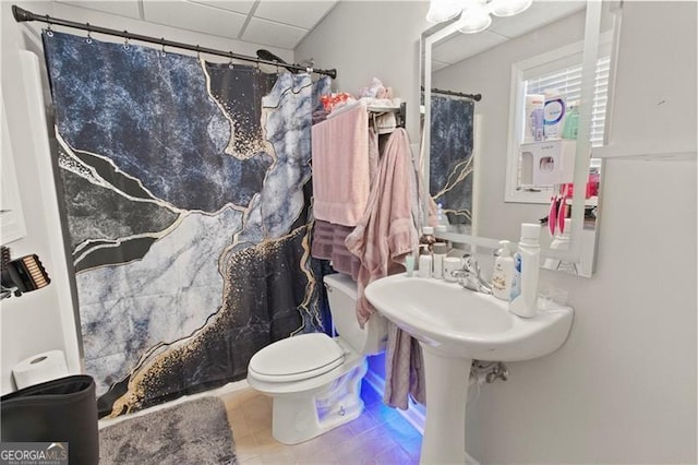 bathroom featuring a drop ceiling, curtained shower, and toilet