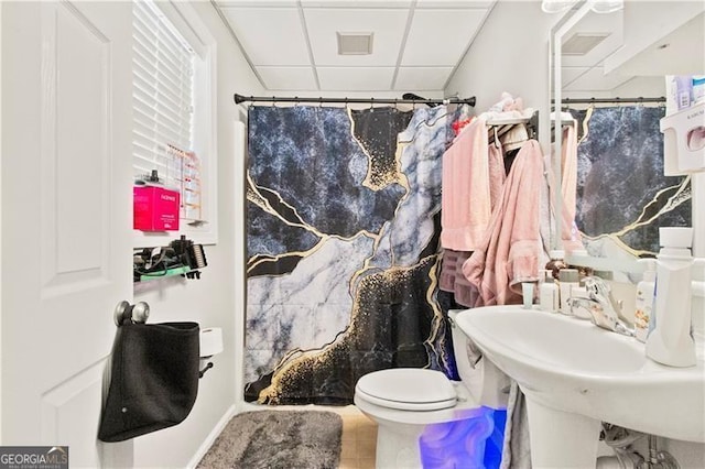 bathroom featuring walk in shower, a paneled ceiling, tile patterned floors, and toilet