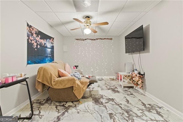 living area featuring a paneled ceiling and ceiling fan