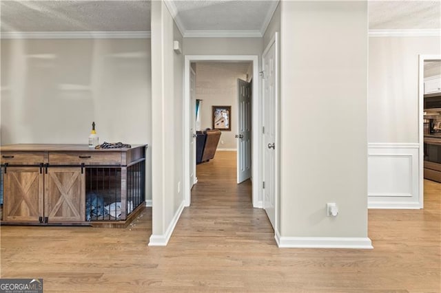 hallway featuring ornamental molding, light hardwood / wood-style flooring, and a textured ceiling