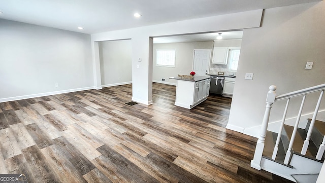 kitchen featuring dishwasher, wood-type flooring, white cabinets, a kitchen island, and decorative backsplash