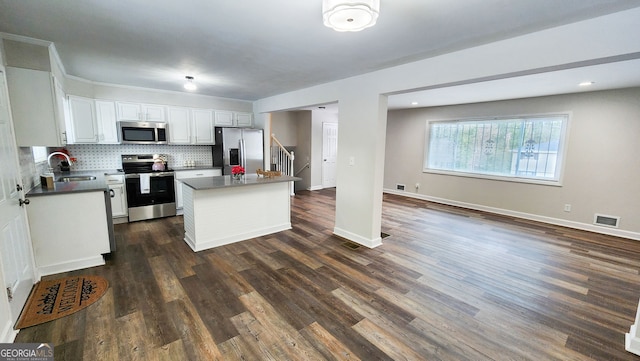 kitchen with sink, stainless steel appliances, white cabinets, a kitchen island, and decorative backsplash