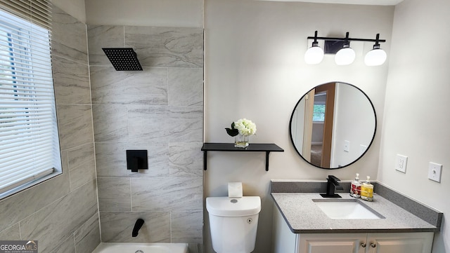 full bathroom featuring vanity, tiled shower / bath, and toilet