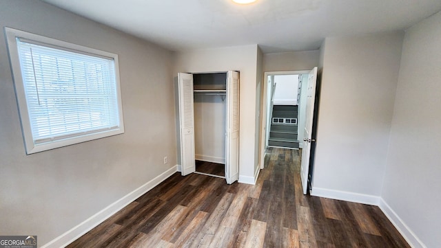 unfurnished bedroom with dark hardwood / wood-style floors and a closet