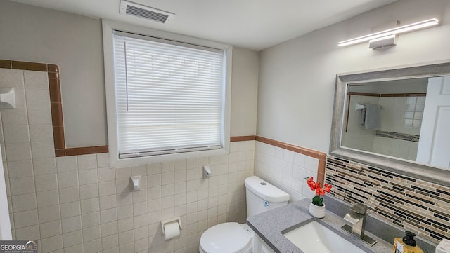 bathroom featuring vanity, tile walls, and toilet