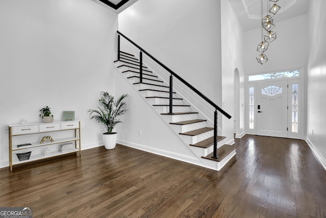 entrance foyer with dark wood-type flooring and a towering ceiling