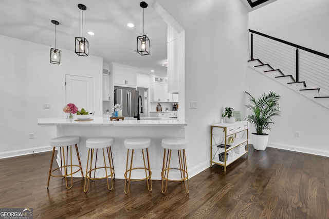 kitchen with pendant lighting, sink, stainless steel fridge, white cabinets, and kitchen peninsula