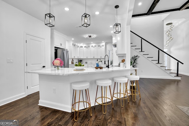 kitchen featuring dark wood-type flooring, stainless steel fridge, decorative light fixtures, and white cabinets