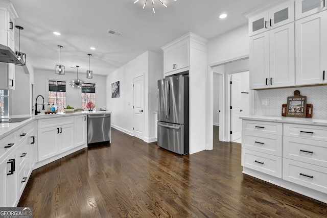 kitchen featuring appliances with stainless steel finishes, decorative light fixtures, white cabinetry, dark hardwood / wood-style flooring, and decorative backsplash