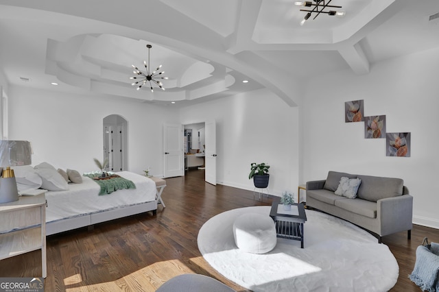 bedroom featuring an inviting chandelier, dark wood-type flooring, and a raised ceiling