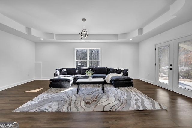 living room with a tray ceiling, dark wood-type flooring, and french doors