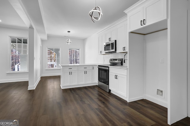 kitchen featuring appliances with stainless steel finishes, hanging light fixtures, white cabinets, decorative backsplash, and kitchen peninsula