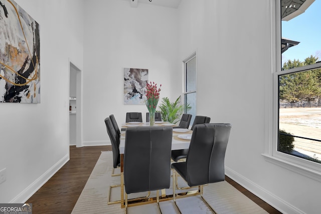 dining area featuring a towering ceiling and dark hardwood / wood-style floors