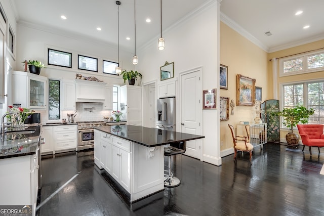 kitchen featuring high quality appliances, sink, a breakfast bar area, white cabinets, and a center island