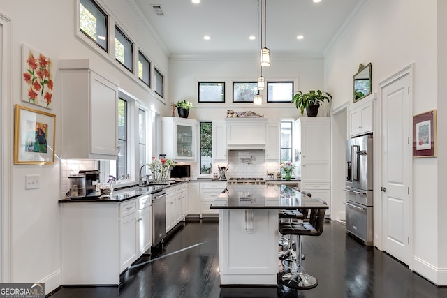 kitchen featuring white cabinetry, appliances with stainless steel finishes, a kitchen breakfast bar, and a center island