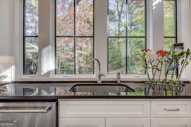 kitchen featuring dishwasher, sink, dark stone countertops, and white cabinets