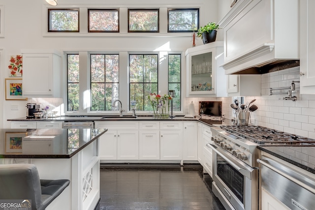 kitchen featuring sink, dark stone countertops, white cabinets, decorative backsplash, and stainless steel appliances