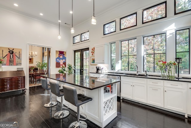 kitchen with sink, white cabinetry, stainless steel dishwasher, a kitchen island, and pendant lighting