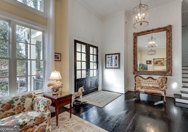 foyer featuring an inviting chandelier, crown molding, hardwood / wood-style floors, and french doors