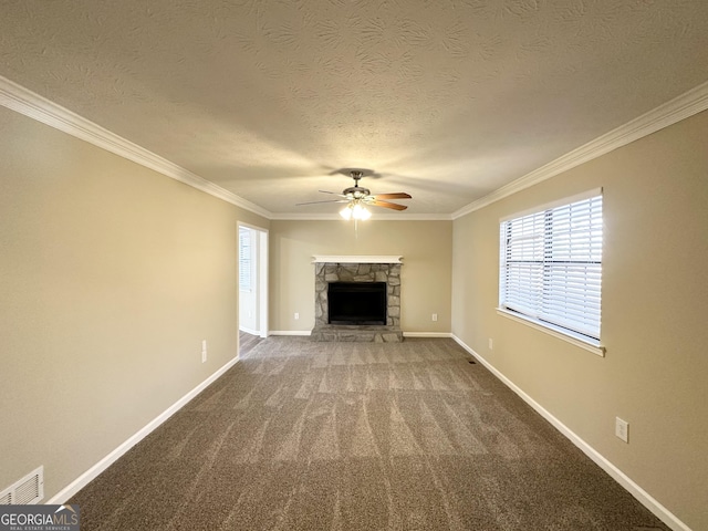 unfurnished living room featuring a stone fireplace, crown molding, a textured ceiling, carpet floors, and ceiling fan