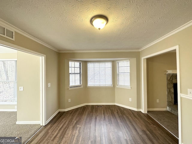 unfurnished room with a healthy amount of sunlight, a textured ceiling, dark wood-type flooring, and a fireplace