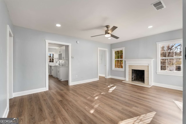 unfurnished living room featuring wood-type flooring, sink, and a wealth of natural light