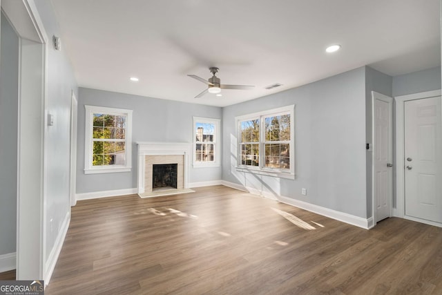 unfurnished living room featuring plenty of natural light, dark hardwood / wood-style floors, and ceiling fan