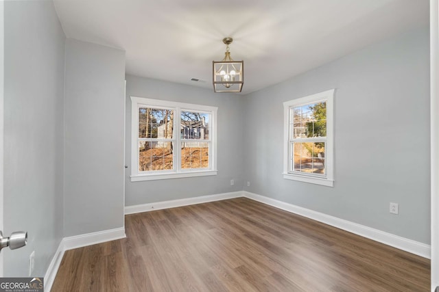 spare room featuring wood-type flooring and a notable chandelier