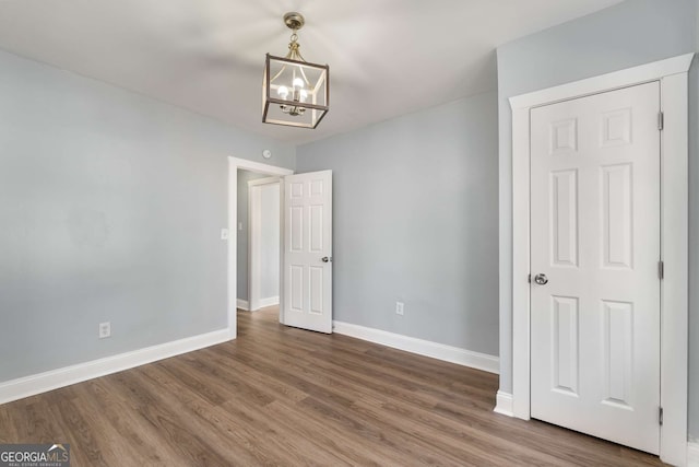 unfurnished bedroom with dark hardwood / wood-style flooring and a notable chandelier