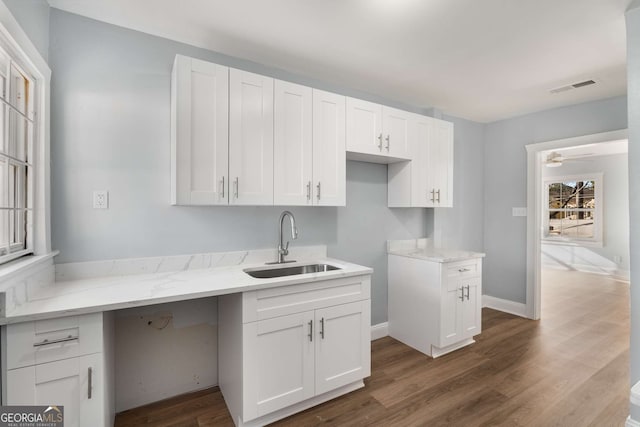 kitchen featuring white cabinetry, sink, light stone countertops, and dark hardwood / wood-style floors