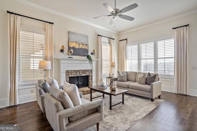 living room featuring ceiling fan, ornamental molding, dark hardwood / wood-style flooring, and a stone fireplace