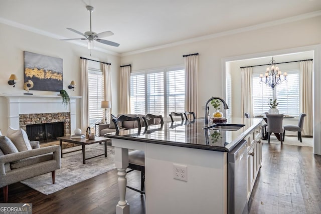 kitchen with a kitchen bar, sink, a center island with sink, stainless steel dishwasher, and a wealth of natural light