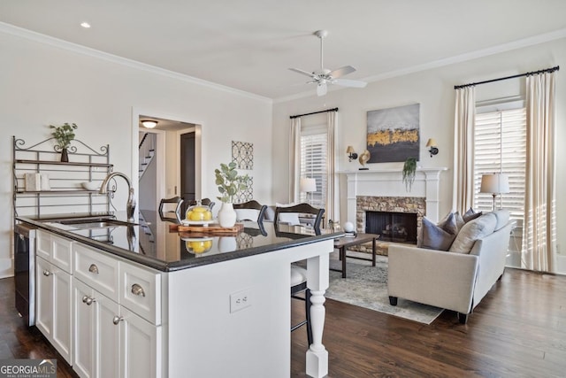 kitchen with sink, a breakfast bar area, plenty of natural light, an island with sink, and white cabinets