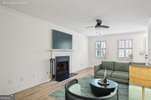 living room featuring ceiling fan, light hardwood / wood-style flooring, and crown molding