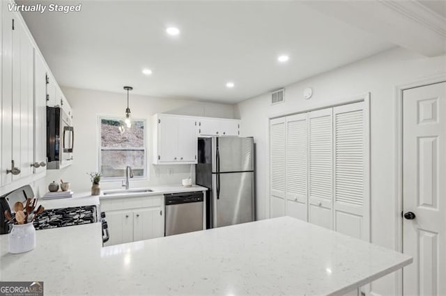 kitchen featuring white cabinetry, sink, hanging light fixtures, and stainless steel appliances