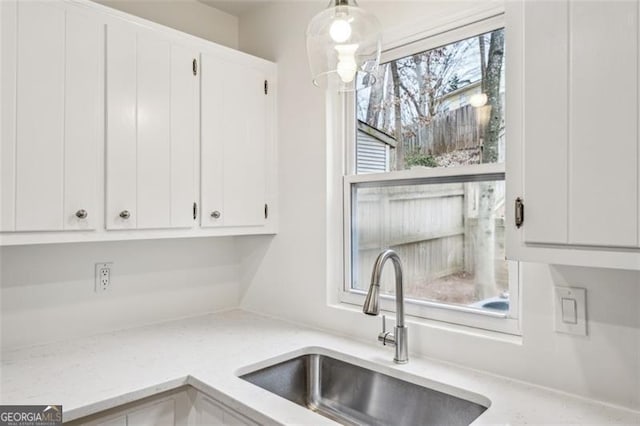 kitchen featuring white cabinetry, sink, and pendant lighting