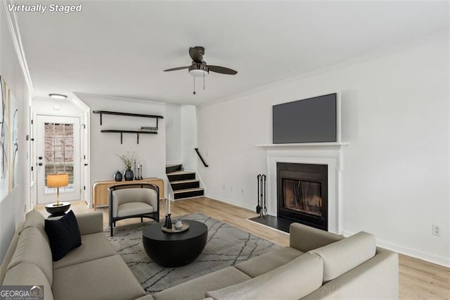 living room featuring light wood-type flooring, ceiling fan, and ornamental molding