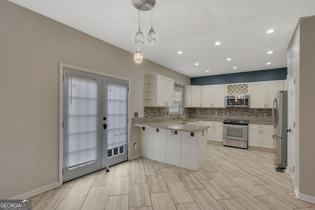 kitchen featuring white cabinetry, hanging light fixtures, stainless steel appliances, tasteful backsplash, and kitchen peninsula