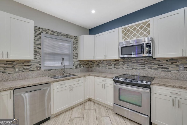 kitchen featuring light stone countertops, appliances with stainless steel finishes, sink, and white cabinets