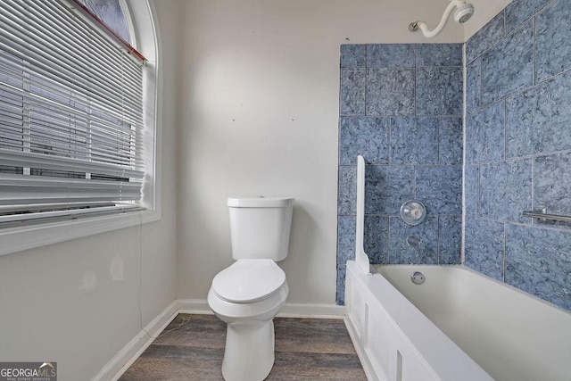 bathroom featuring hardwood / wood-style flooring, tiled shower / bath, and toilet