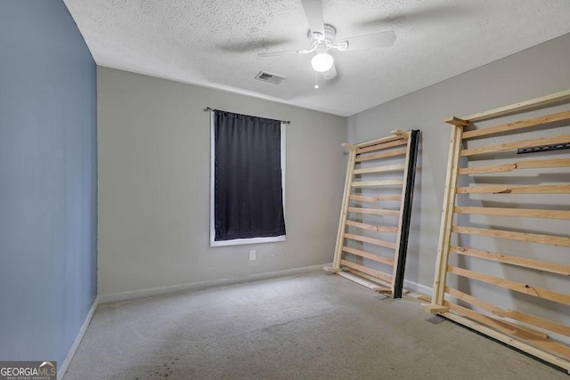 carpeted empty room with ceiling fan and a textured ceiling