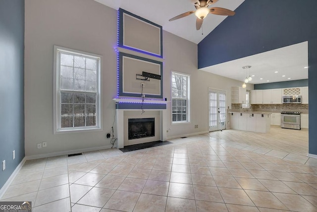 unfurnished living room featuring light tile patterned floors, high vaulted ceiling, and ceiling fan